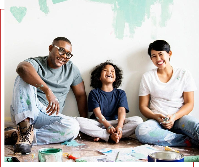 A family sitting on the floor in front of some paint.